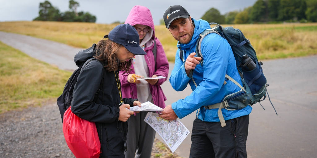 Alex assisting two young people to read a map during a hike