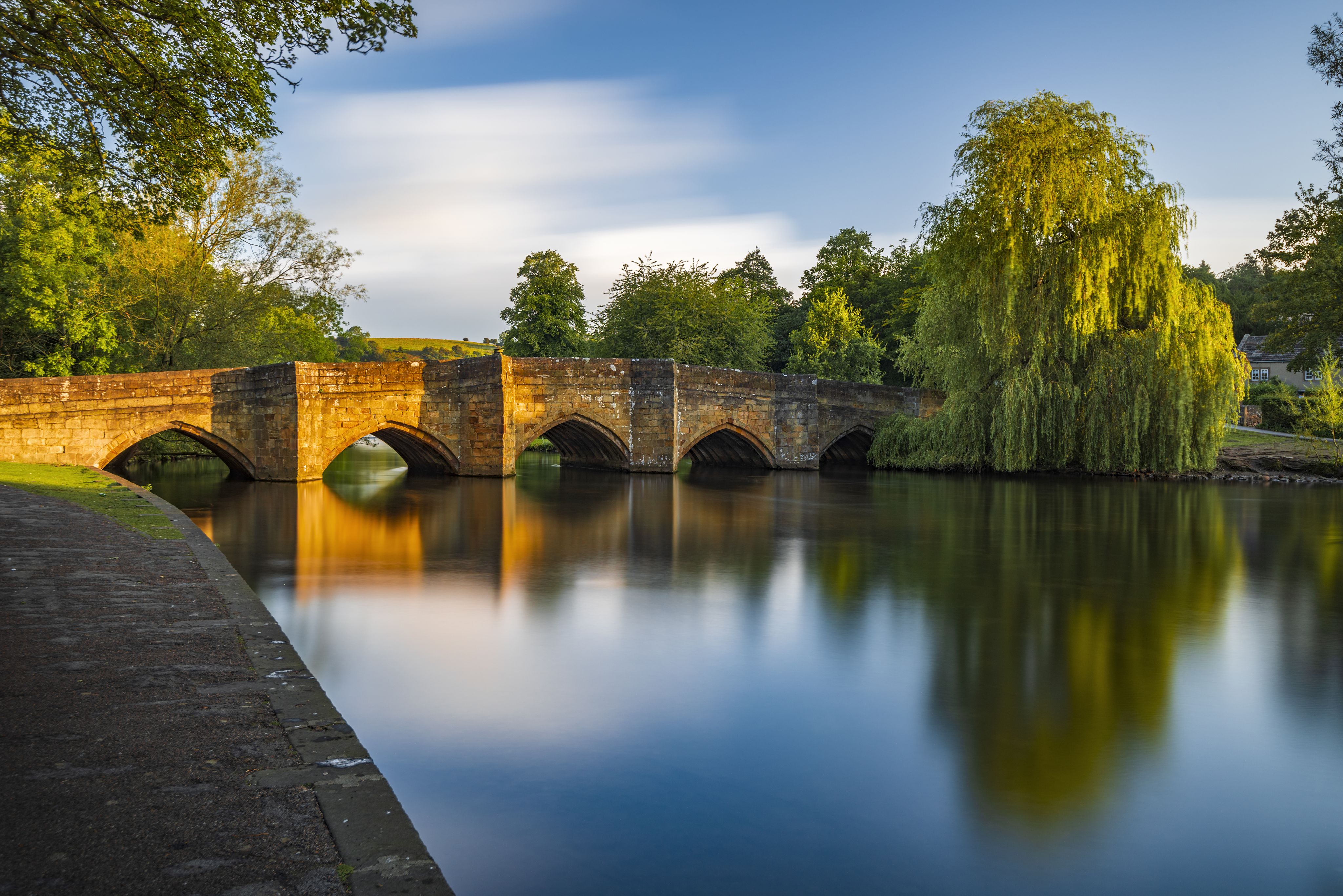 A vaulted stone bridge crosses the tranquil waters of a rural river