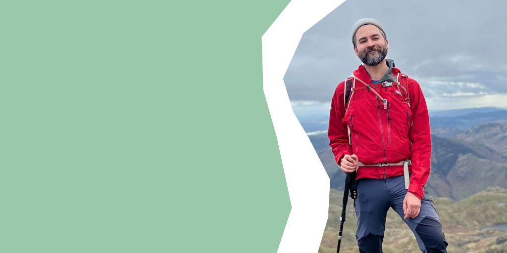 Jonathan smiling at the top of a peak on an overcast day