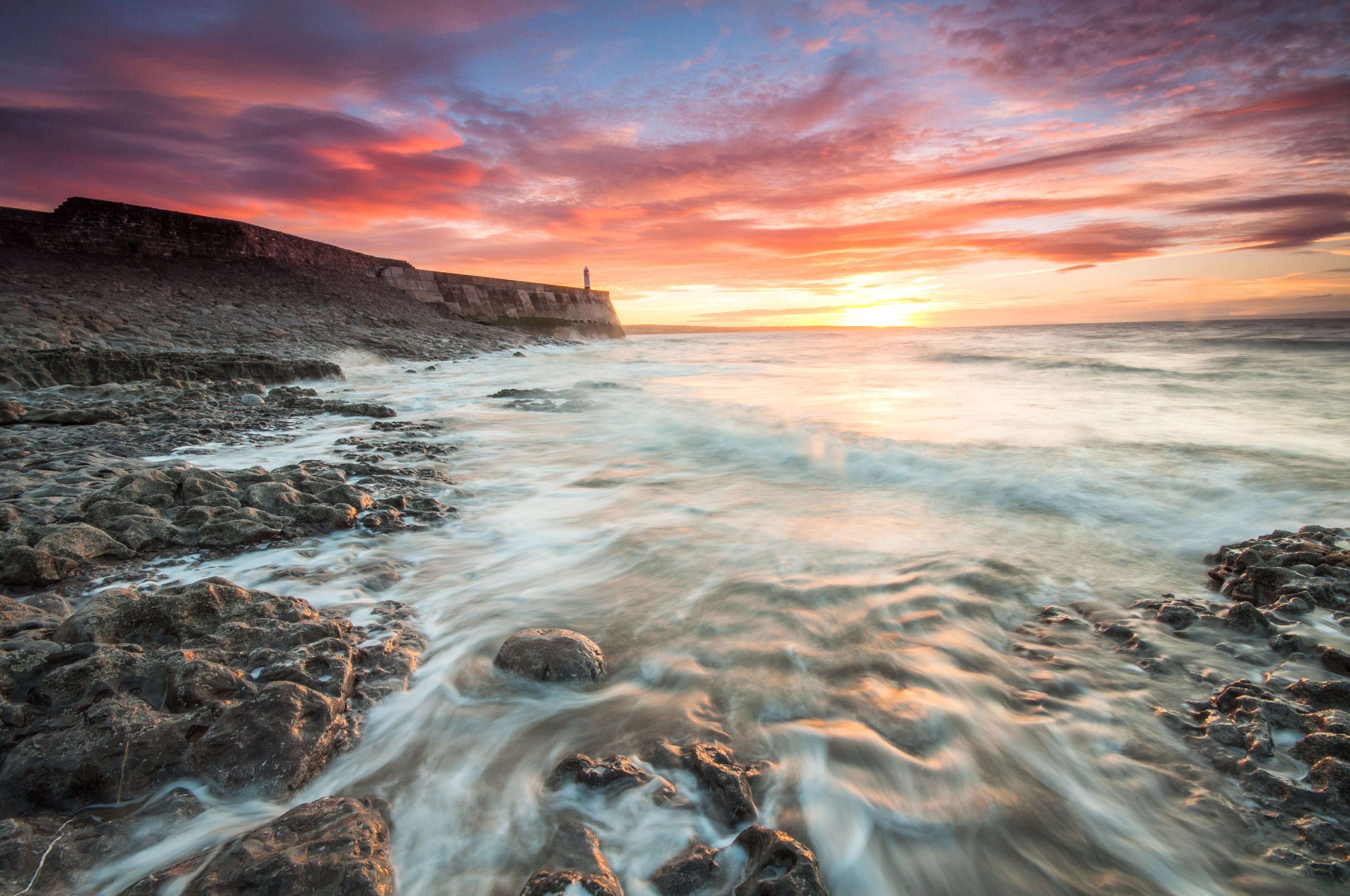 The tide flows over the shore at sunrise on the Welsh coast