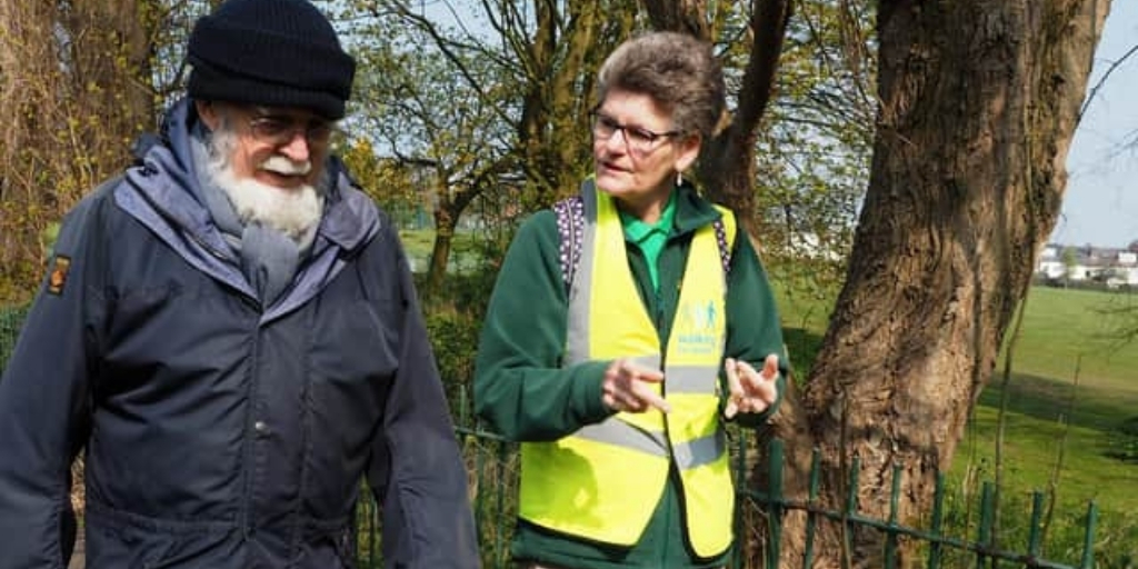 Sue on a walk, talking to another gentleman whilst walking through a park