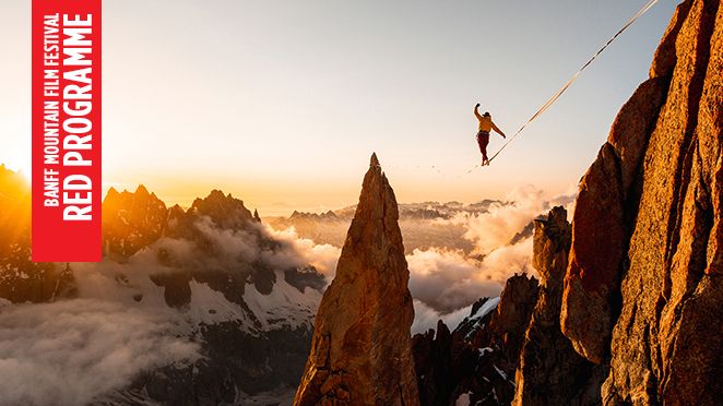 Vertical banner with white text and red background reads Banff Mountain Film Festival Red Programme. Slackliner walks between a rock face and Sharp pinnacle of rock. Snow capped Mountainous terrain in the background is shrouded in cloud. The sun is just behind the peaks to the rear of the image creating a hazy glow in the sky.