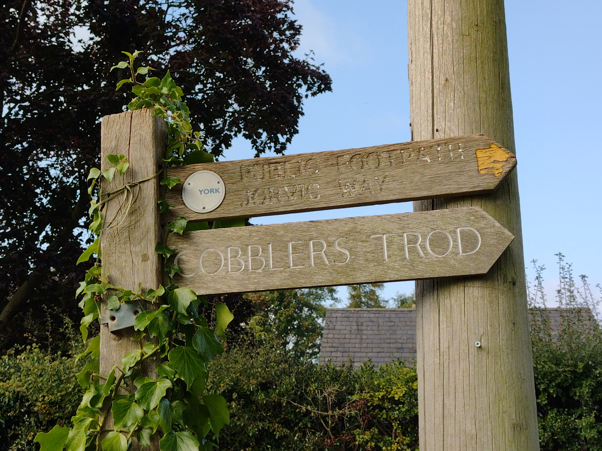 The image shows a footpath sign pointing to Jorvic Way and Cobbler's Trod.