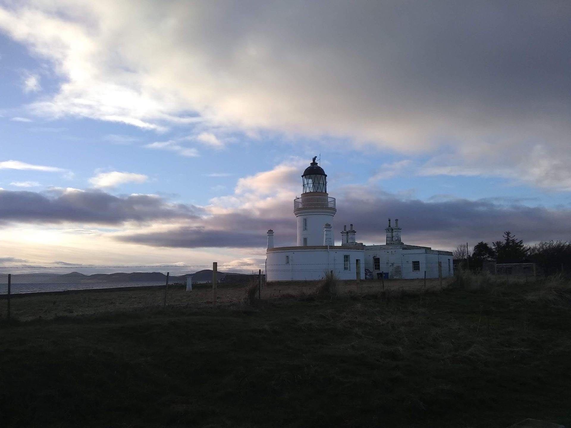 White lighthouse against blue sky with scattered clouds