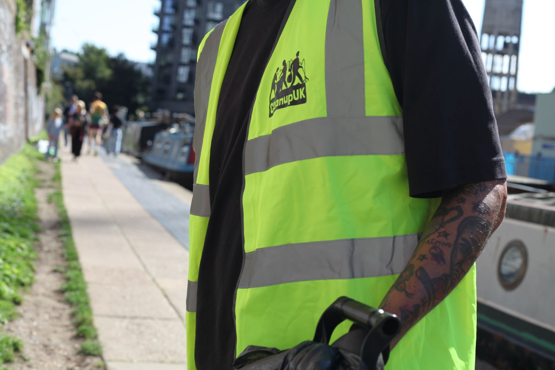 Close up photo of a person wearing a hi vis that has "Cleanup UK Camden Town" written on it