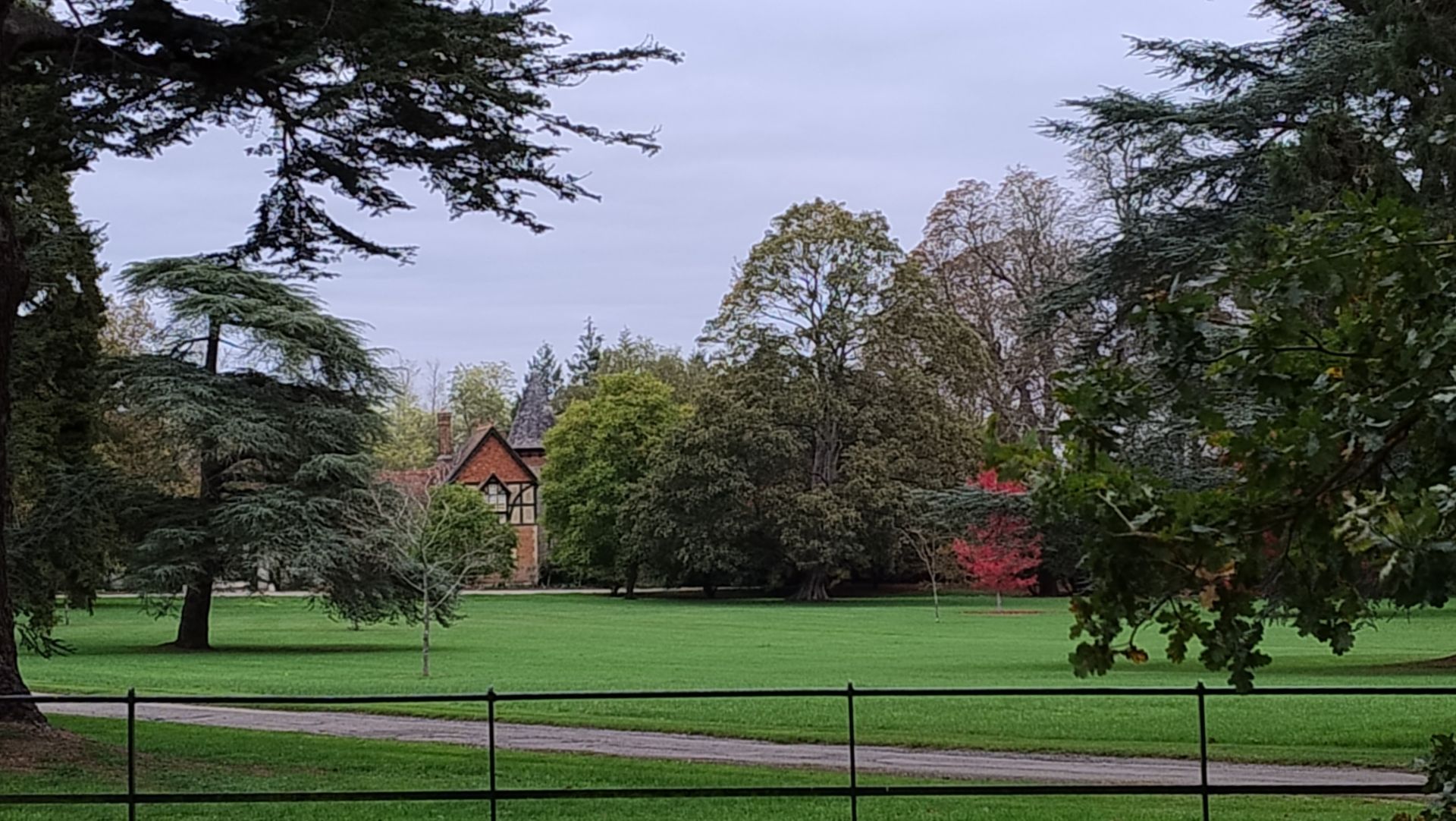 A view of a large country house across a large lawn with trees 