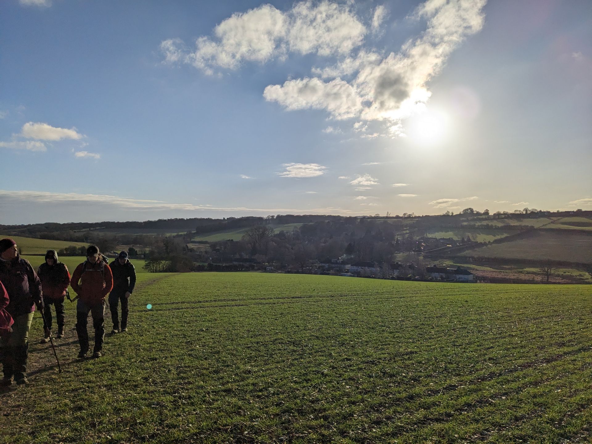 A group of young walkers brave the winter sun and the hills with the sun starting to set behind them