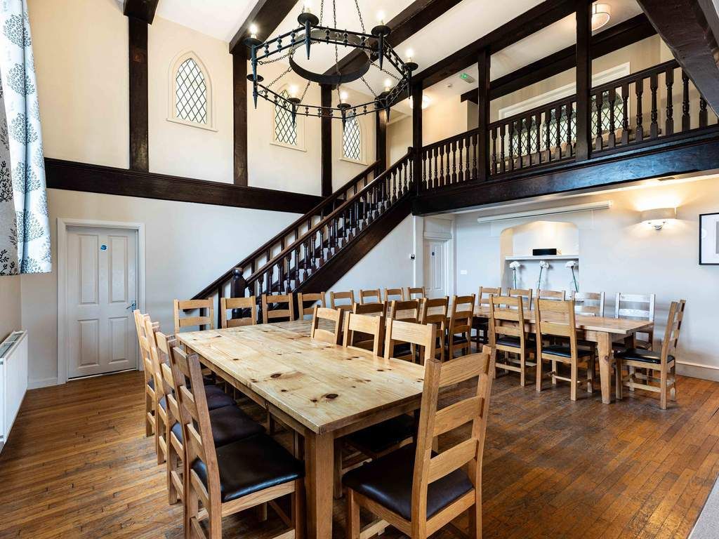 Dining room with large oak tables and chairs, high ceilings and timber beams