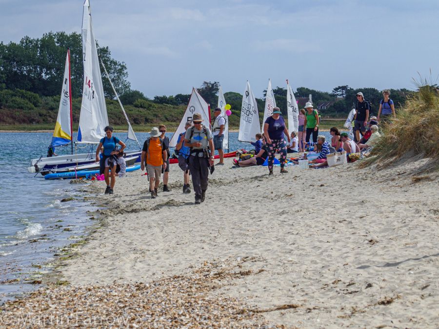 walking across sand boats in background