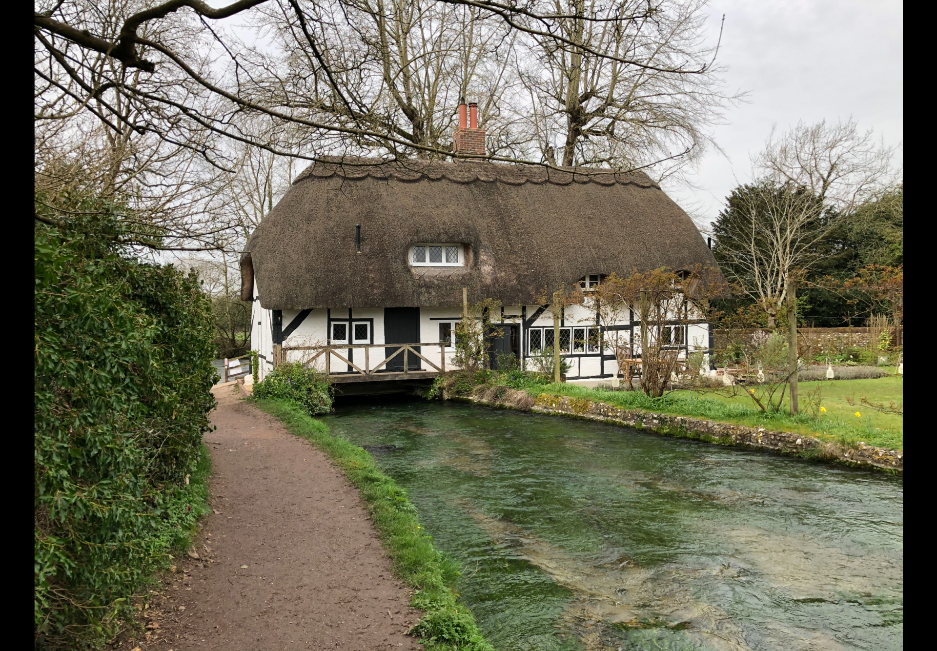 Alongside the River Alre - a thatched building that used to be a fulling mill sits over the river.