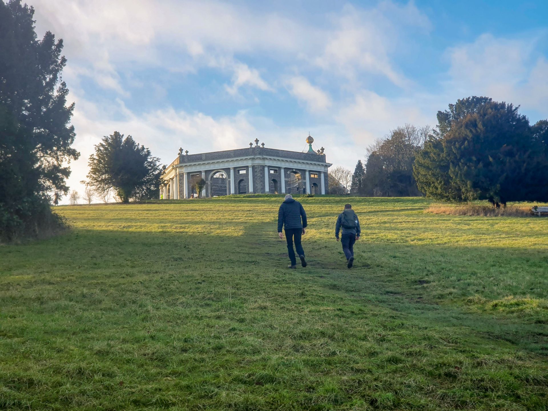 Walkers on path approaching flint building