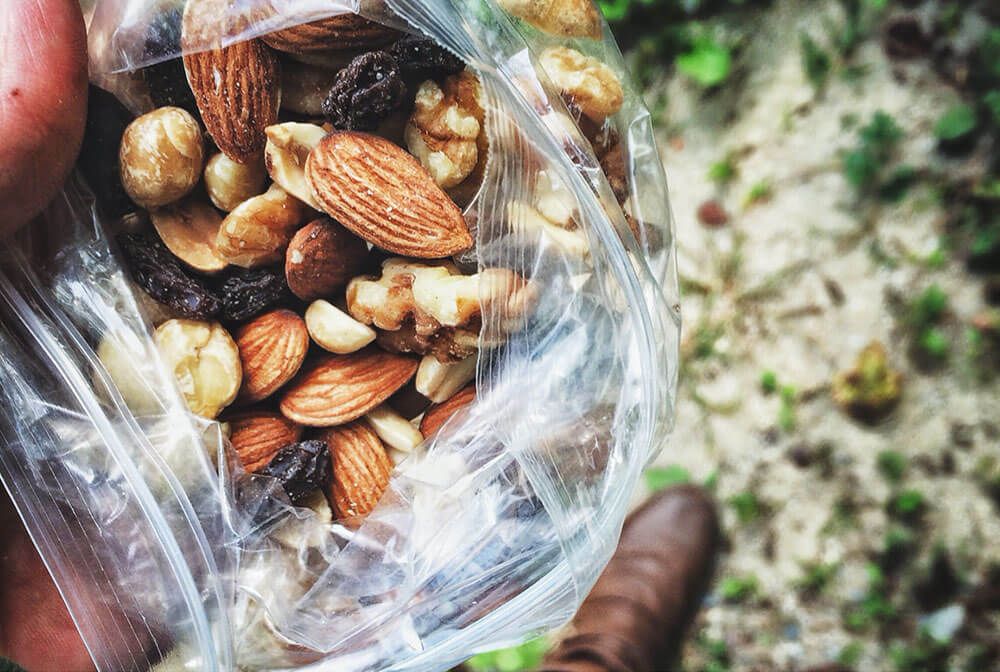 Person's hand holding trail mix, outside