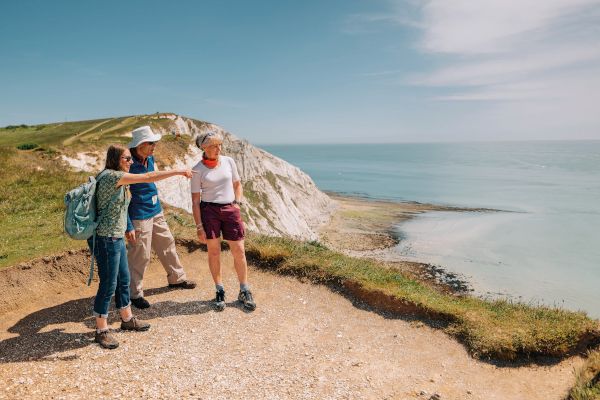 A group of walkers with a cliff behind them pointing into the distance