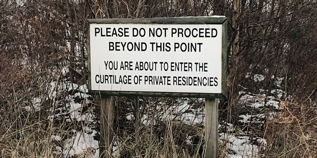 A blocked path with sign saying "PLEASE DO NOT PROCEED BEYOND THIS POINT"