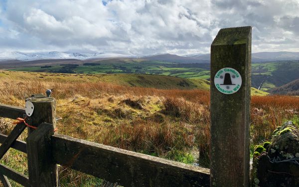 A stile with mountains and a lake in the background