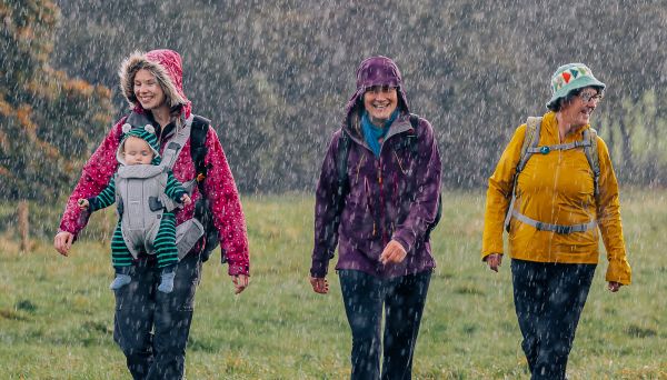 Three women laughing and walking in heavy rain