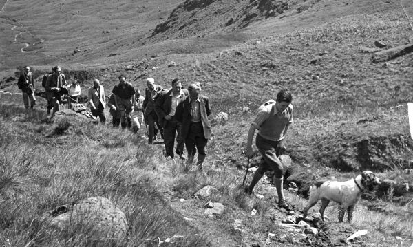 Black and white image of people climbing a hill