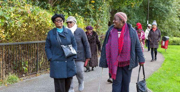 A group of ladies, some using mobility aids, walking in a park