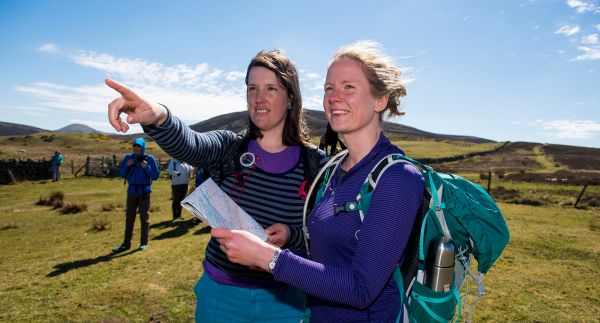 Two female ramblers, looking at a map and pointing in the direction of travel