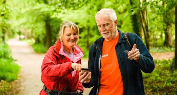 A man and woman referring to a phone and pointing