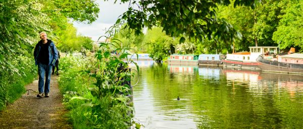 A man walking along a canal towpath