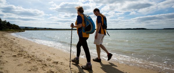 Two people walking along a beach shoreline