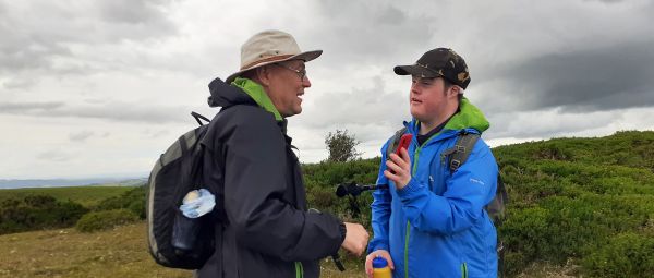 A man and young man, talking, standing on a hill