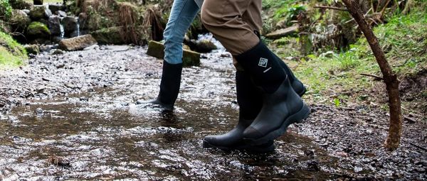 A person wearing wellies, crossing a stream