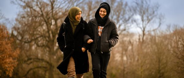 A woman and daughter wearing veils, out walking in autumn