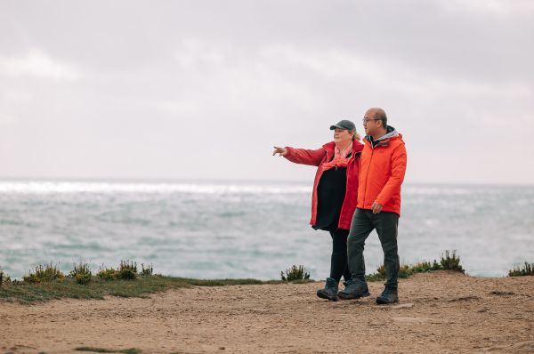 Two people walking along coastline