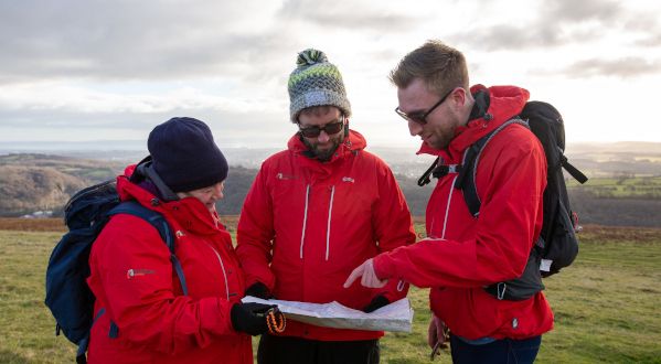 three walkers looking at map in matching red jackets