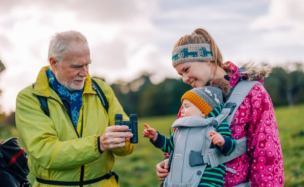 mature ale walker showing child in a baby sling his binoculars 