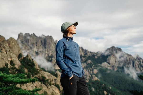 female walker in fleece and cap looking into the distance surrounded by mountains