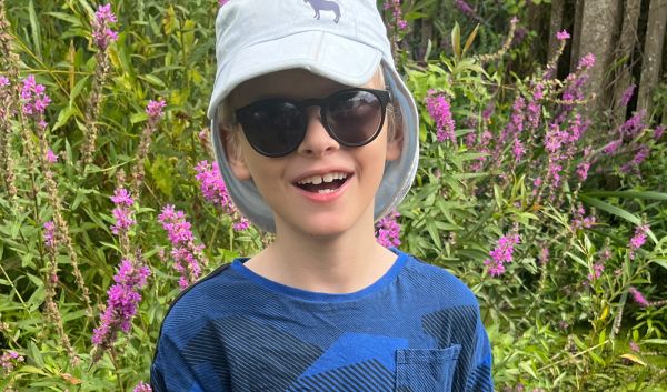 Samuel wearing dark glasses and a cap, holding his walking cane.