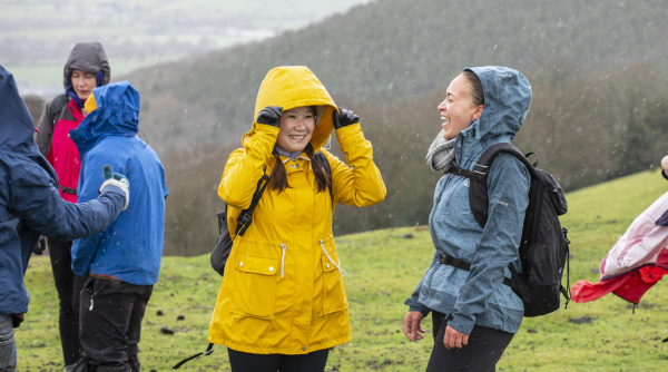 two walkers taking a break from a hill walk, wearing waterproof jackets and backpacks