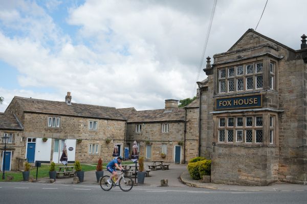 A man cycling passed the Fox House pub in Hathersage
