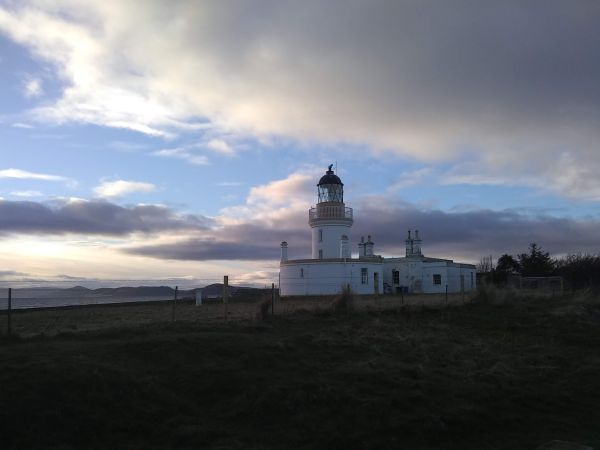 White lighthouse against blue sky with scattered clouds