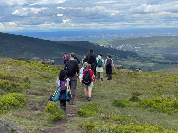 Walkers on an open hillside with a city seen in the distance