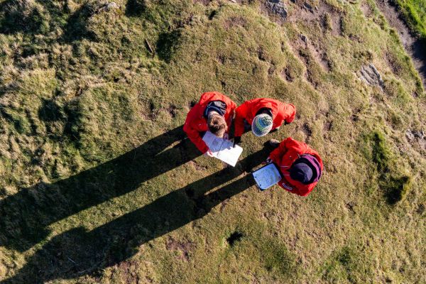 An overhead view of three walkers looking at maps