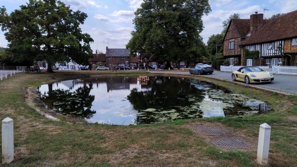 View of Aldbury village pond on a sunny day with reflections of the sky. 