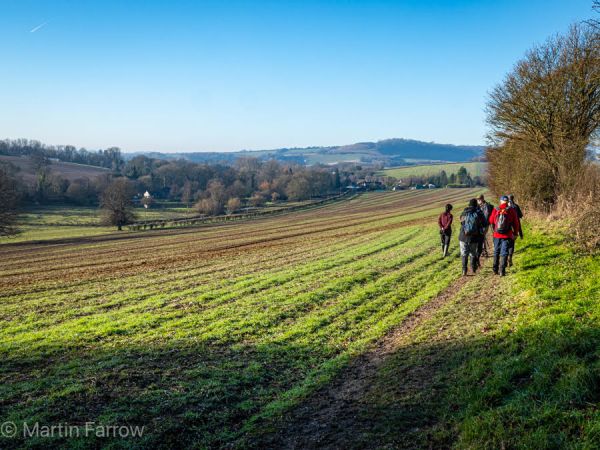Ramblers walking across grass, blue sky