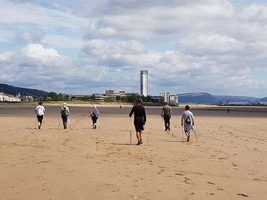 A group of walkers on a beach near Swansea