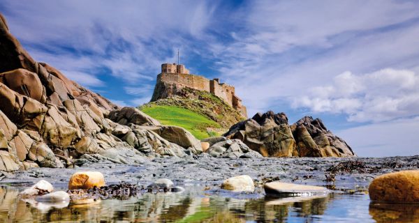 A castle on a hill seen through ocean rocks
