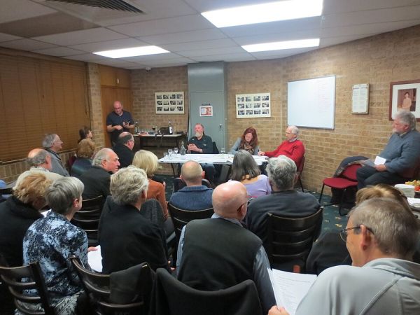 Generic photo of an AGM of a voluntary organisation showing a room full of people seated in front of a top table where committee officers are presenting. Photo is licensed via Creative Commons CC-BY-SA 4.0 by Johnscotausshared courtesy of  