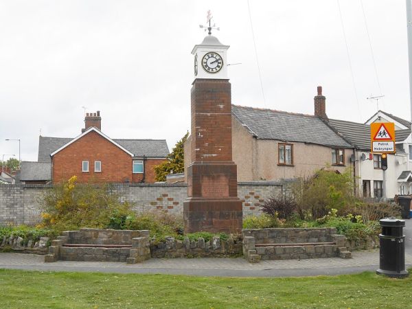 The Millenium Clock in the village of Penyffordd stands on a tall brick pedestal and is flanked by two stone benches