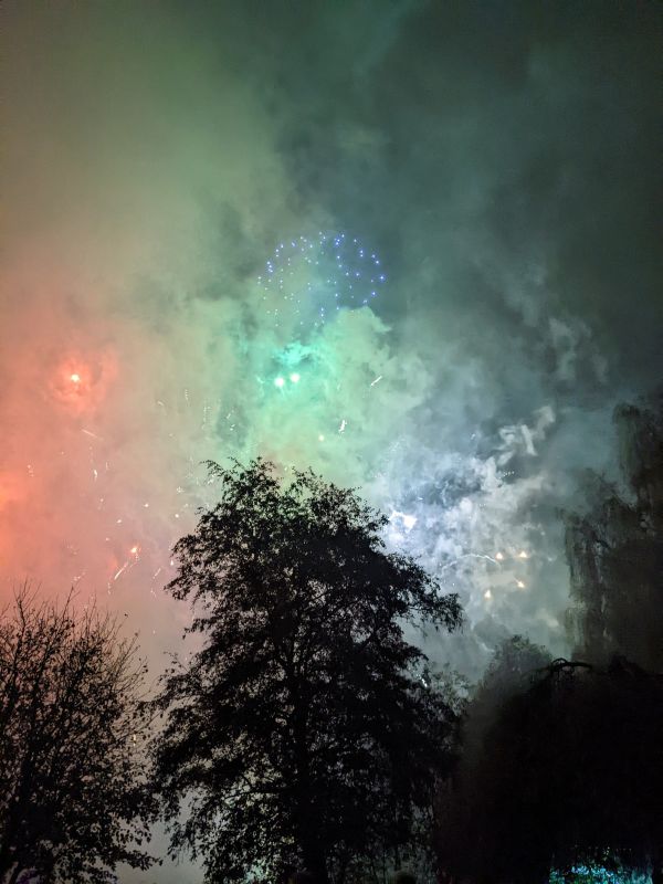 A colourful display  of fireworks behind a haze of smoke
