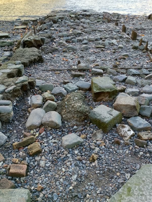 River shore with embedded stones and large pebbles with river water in the background.