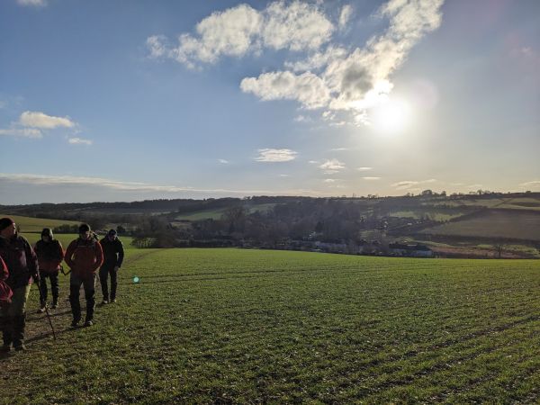 A group of young walkers brave the winter sun and the hills with the sun starting to set behind them