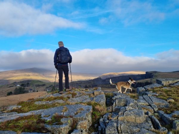 Hiker and dog taking in views from a cliff edge