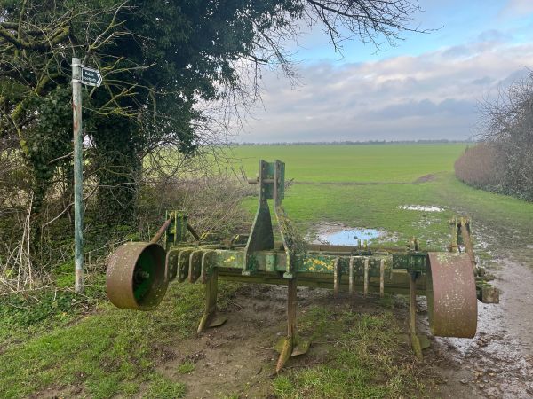 An old farm tool with a view of arable land
